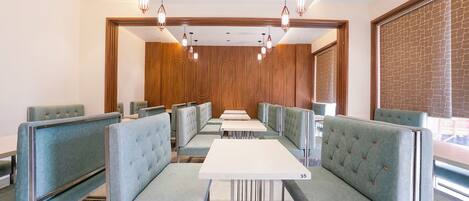 A restaurant with booths and tables, wooden paneling, and hanging pendant lights.