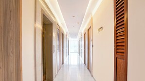 A hotel corridor with doors, a sign indicating 'Floor,' and a view to the outside. - Fabhotel Prime Shree Palace (Palghar)