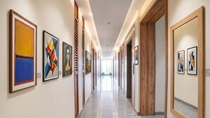 A hallway with framed artworks on the walls, wooden doors, and a marble floor. - Fabhotel Prime Shree Palace (Palghar)
