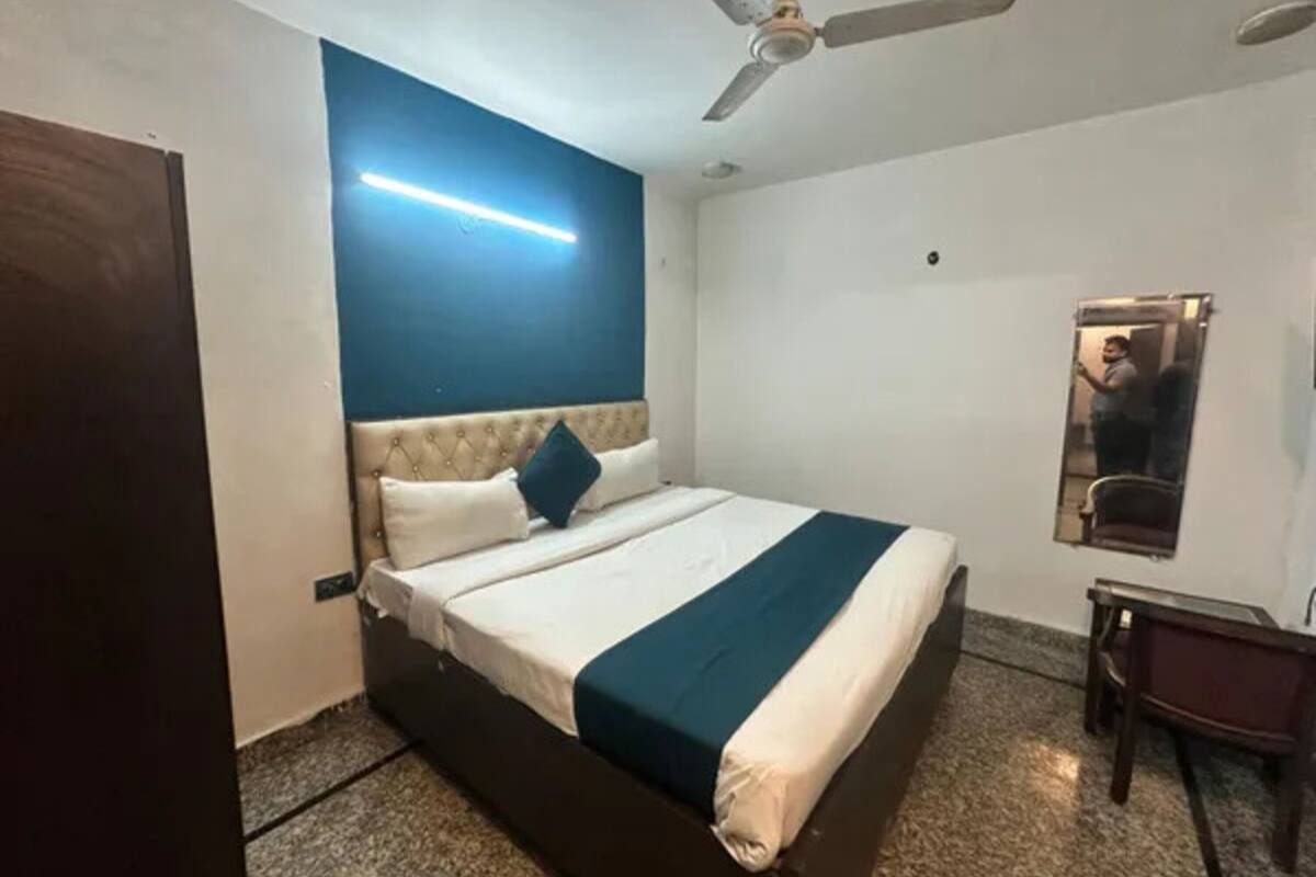 A bedroom with a bed, a ceiling fan, a night light, a mirror, and a small table.