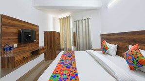 A hotel room with a bed, a TV mounted on a wooden panel, a wardrobe, and a shower area. - Fabhotel Sky Sector 76 (Gurugram)