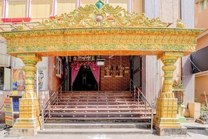 A temple entrance with ornate golden pillars, a staircase leading to the main hall, and a sign indicating room availability. - Fabhotel Yazhini Residency (Chennai)