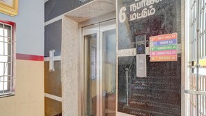 Ein Hotel Eingang mit Glastür, Hinweisschild für den Erdgeschoss und Verzeichnis für verschiedene Hallen und Räume.