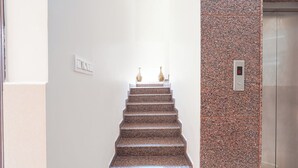 A staircase with a granite finish, leading to a landing with two decorative vases. - Fabhotel Wagtail - Opp Wipro Corporate Office, Sarjapur (Bangalore)