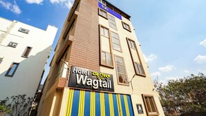A hotel named 'Hotel Wagtail' with a sign in multiple languages, a brick facade, and a clear sky. - Fabhotel Wagtail - Opp Wipro Corporate Office, Sarjapur (Bangalore)