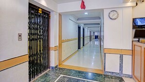 A hotel corridor with a black gate, a clock, and a television on the wall. - Fabhotel Dukes Plaza (Mumbai)