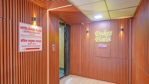 A hotel interior with a wooden panel wall, a neon sign for 'Hotel Dukes Plaza,' and a lift service sign for the 2nd floor. - Fabhotel Dukes Plaza (Mumbai)
