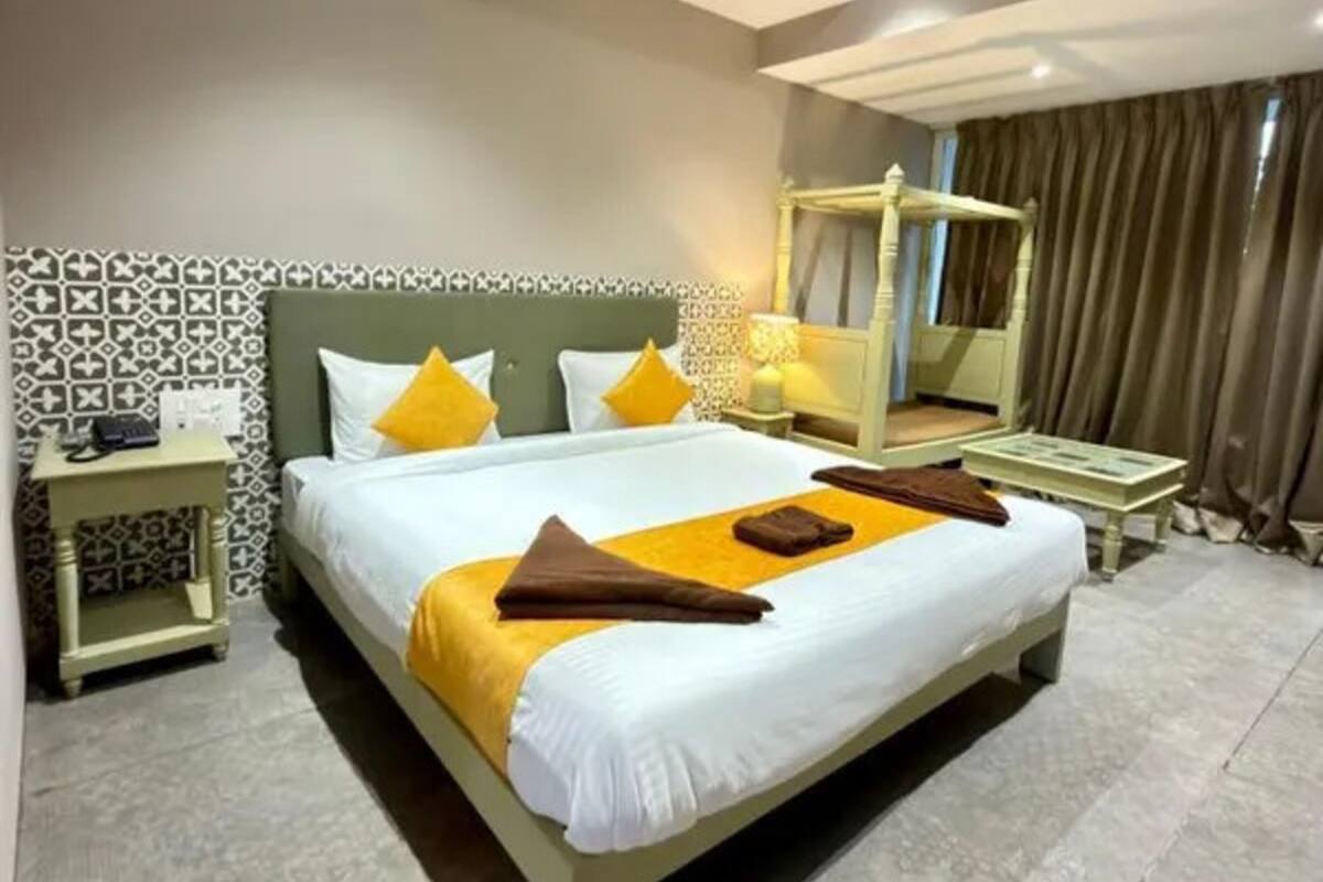 A neatly arranged hotel room with a large bed, bedside tables, a bedside lamp, and a canopy bed.