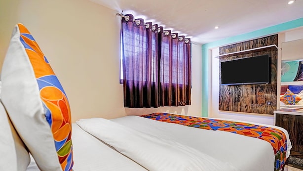 A hotel room with a bed, curtains, a TV, and a wall with a textured design. - Fabhotel Orange Residency (Mumbai)