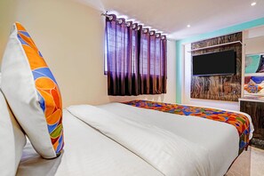 A hotel room with a bed, curtains, a TV, and a wall with a textured design. - Fabhotel Orange Residency (Mumbai)
