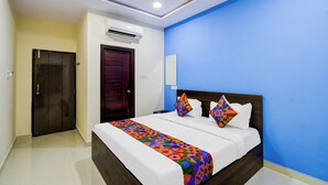 A hotel room with a bed, a door, an air conditioning unit, and a blue wall. - Fabhotel Golden City Inn (Hyderabad)