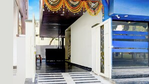 A hallway with a wet floor, a chair, and a staircase leading to a blue door. - Fabhotel Golden City Inn (Hyderabad)