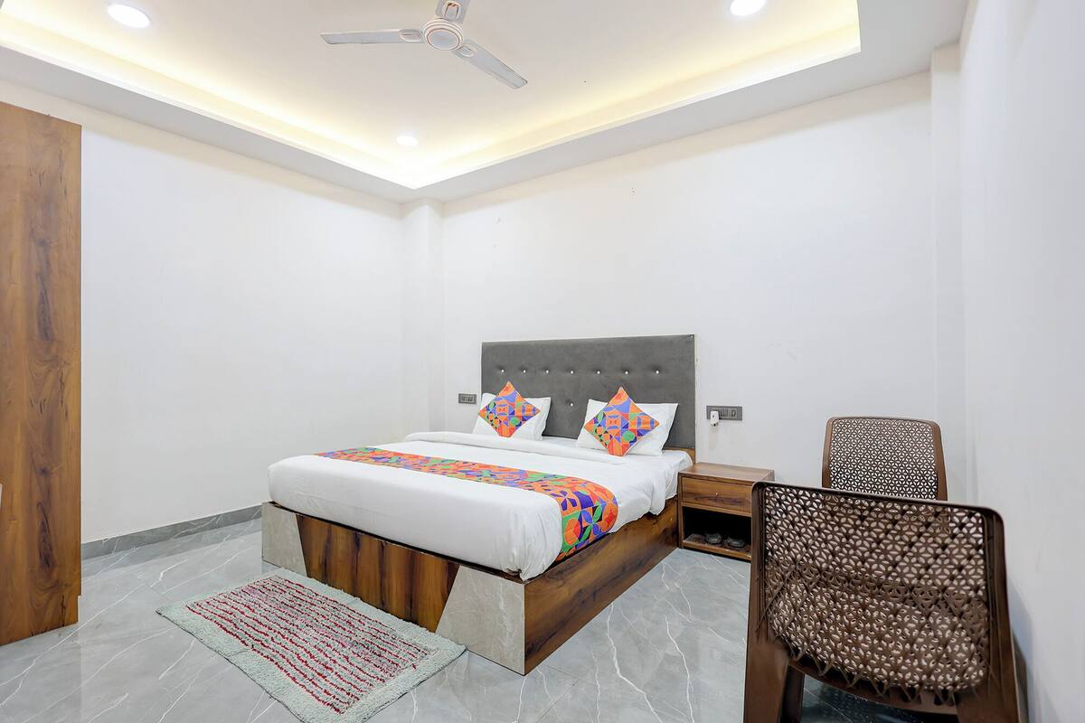 A bedroom with a bed, a chair, a nightstand, and a ceiling fan.