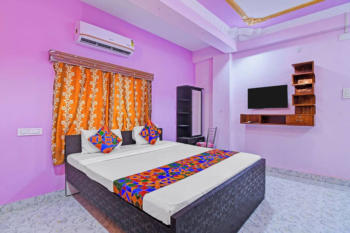 A bedroom with a bed, an air conditioner, a TV, and a wardrobe.