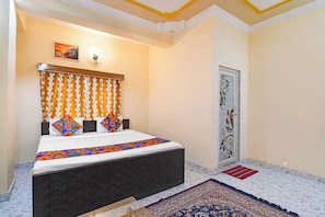 A bedroom with a bed, patterned curtains, a decorative wall, and a door with intricate designs. - Via Safehome Guest House (Barasat)