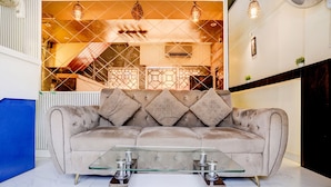 A living room with a beige sofa, a glass coffee table, and a patterned wall. - Fabhotel Nm (Mumbai)
