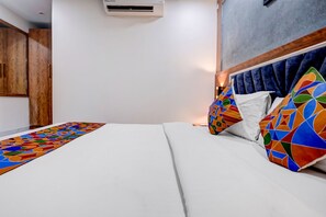 Una habitación de hotel con una cama, un armario de madera y aire acondicionado instalado en la pared.