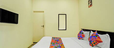 A hotel room with a bed, a television mounted on the wall, and a door.