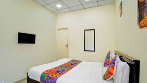 Una camera d'albergo con un letto, una televisione, una porta e uno specchio.