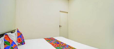 A bedroom with a bed, a door, and a wall with a poster.