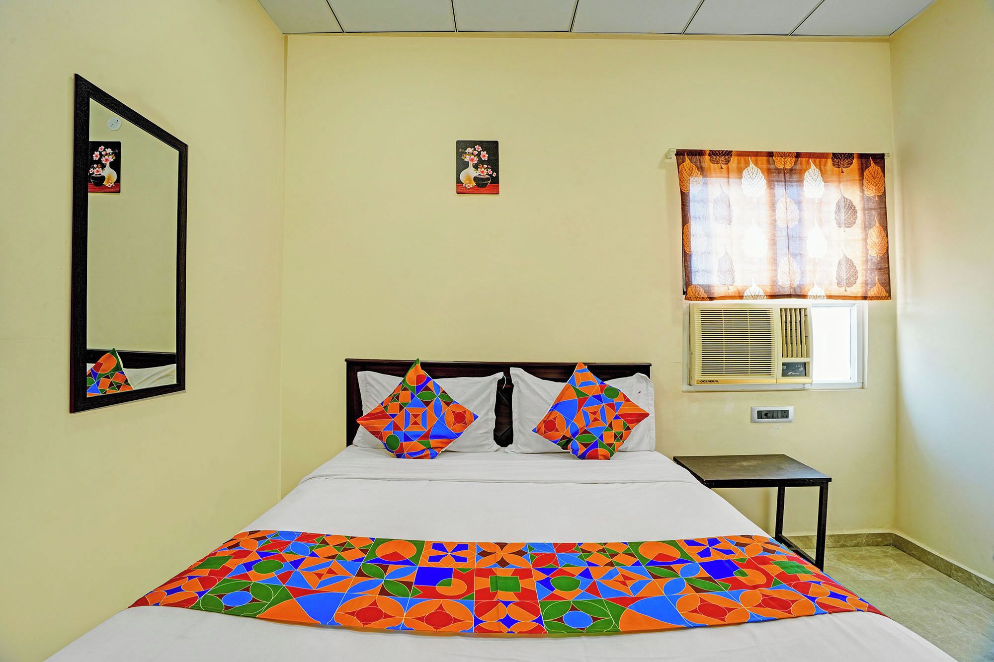 Une chambre à coucher avec un lit, des oreillers, un miroir, une fenêtre avec des rideaux et un appareil de climatisation.