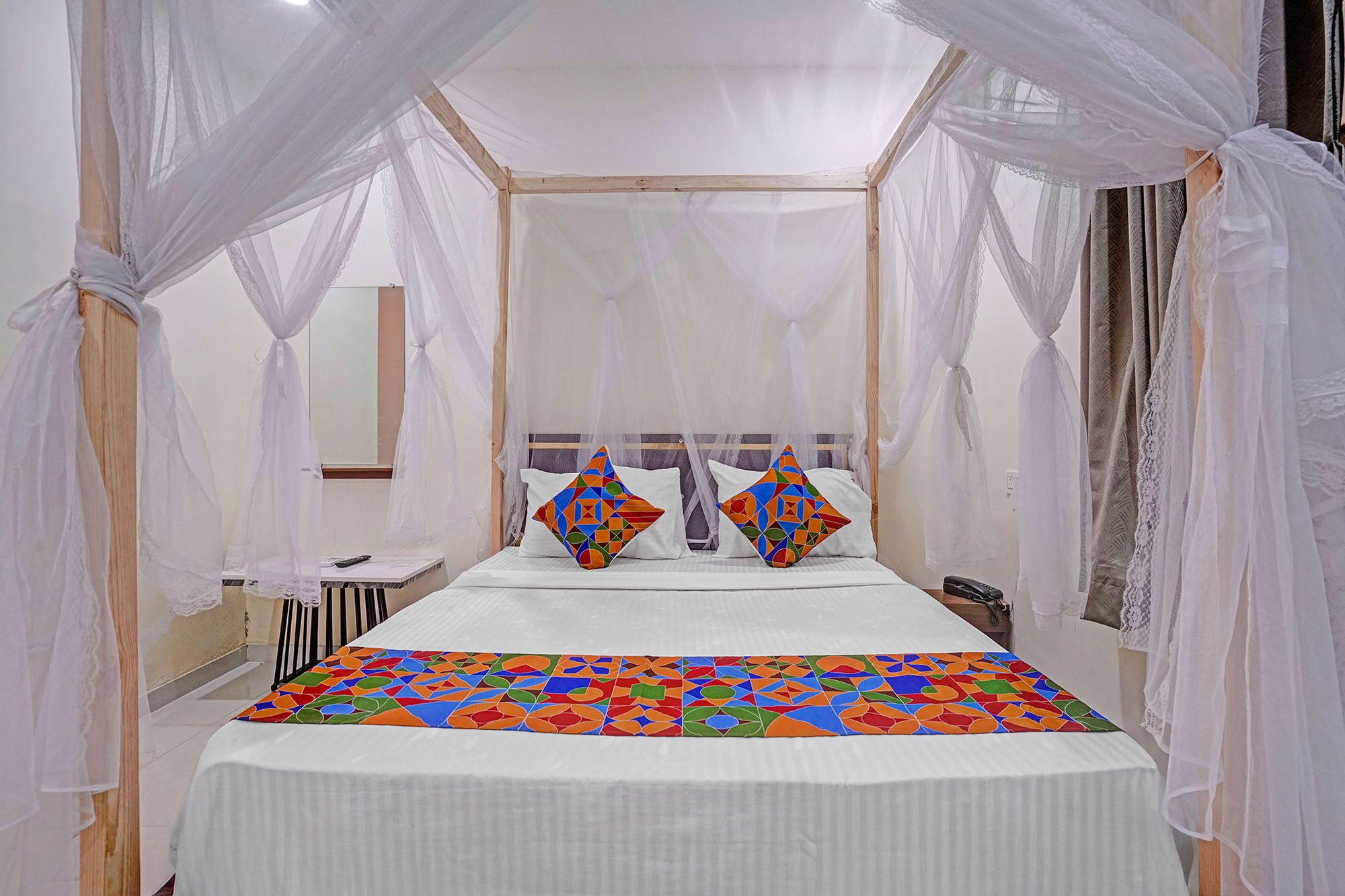A bed with a canopy, a bedside table, and a mirror.