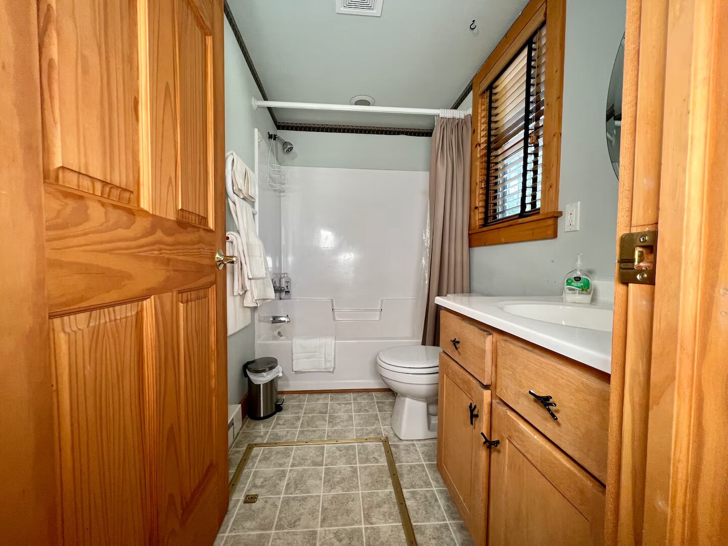 A bathroom with a shower, toilet, and wooden cabinets.