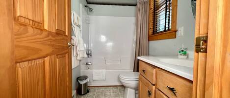 A bathroom with a shower, toilet, and wooden cabinets.