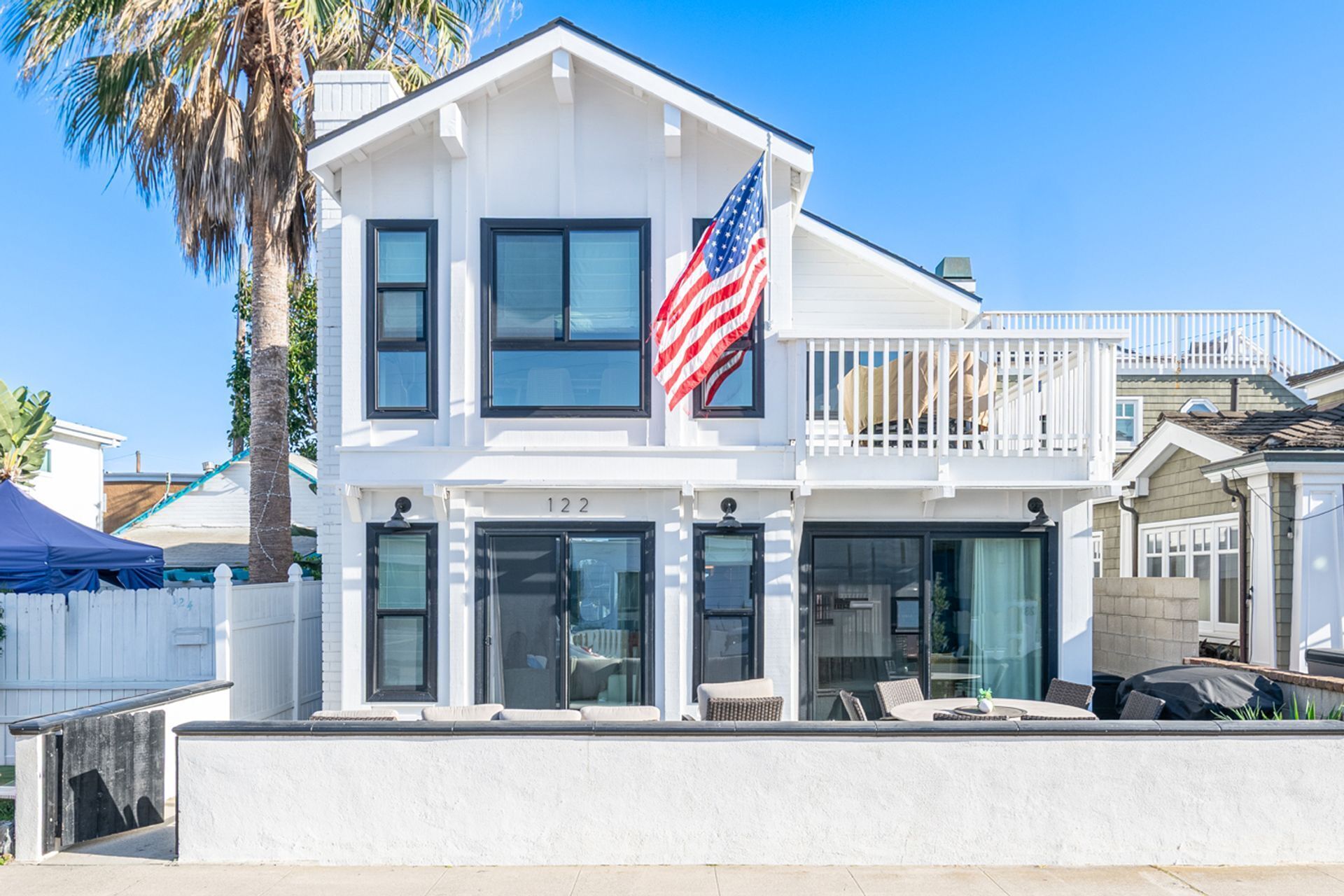 A two-story house with a balcony, a flag, and a number '122' on the front.