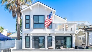 Une maison à deux étages avec un balcon, un drapeau et le numéro « 122 » sur la façade.