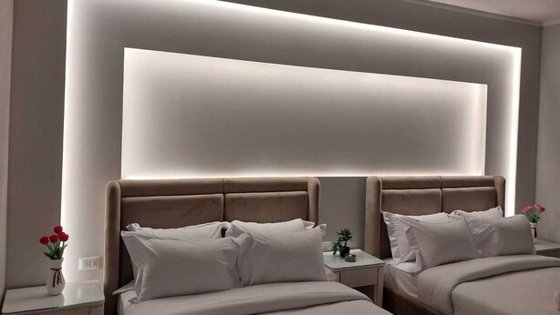 Ein modernes Hotelzimmer mit einem großen Bett, Nachttischen und einer wandmontierten Lampe.