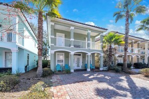 A two-story building with a balcony, palm trees, and a brick pathway. - Beach Tram-Resort Pool-CoCo Bliss (Destin)