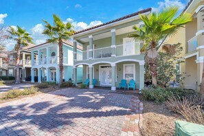 A two-story building with a balcony, palm trees, and a brick pathway. - Beach Tram-Resort Pool-CoCo Bliss (Destin)