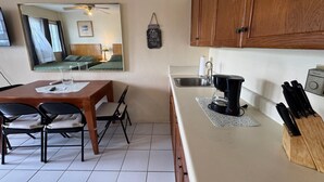 Cozinha compacta com armários de madeira, cafeteira, pia e porta-facas.