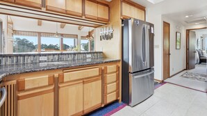 Una cocina con armarios de madera, un refrigerador de acero inoxidable y una encimera de granito.