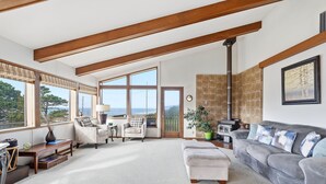 Amplia sala de estar con techo alto, ventanas grandes, chimenea y vista al exterior.
