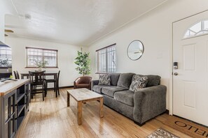 A living room with a sofa, coffee table, and dining area with chairs and a table. - Charming 3-bedroom house in Denver, Quiet with Yard and Easy Commute (Denver)