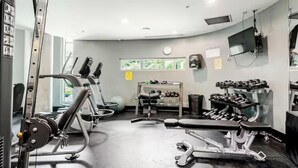 Une salle de sport équipée de machines de cardio, de bancs de musculation et d’haltères.