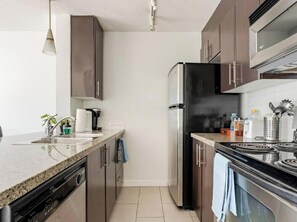 A modern kitchen with stainless steel appliances, a granite countertop, and wooden cabinets.