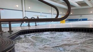 A hot tub area with a curved metal railing, a tiled floor, and a skylight above. - Vancouver downtown apartment (Vancouver)