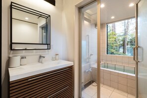 Une salle de bain moderne avec une douche à l’italienne en verre, un grand miroir et un meuble-lavabo blanc.