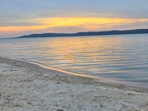 Une plage où l’eau est calme et reflète le ciel.