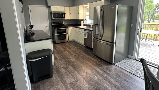 Una cocina compacta con refrigerador, microondas, horno y pileta.