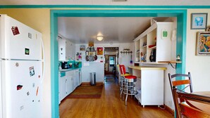 Una cocina con suelo de madera, armarios blancos y una pared de acento color aguamarina.