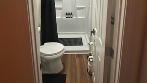Ein Badezimmer mit Toilette, einer Dusche mit schwarzem Duschvorhang und einer Badewanne.