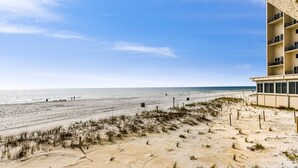 Un hotel frente a la playa con arena, cielo despejado y vista al océano.