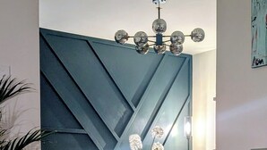 Een moderne eethoek met een geometrisch wandontwerp, een kroonluchter en een verzameling vinylplaten.