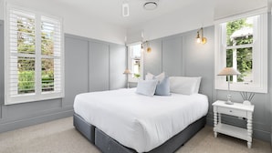 A bedroom with a large bed, two bedside tables, a ceiling fan, and windows with blinds. - The Homestead at Farmhouse Hunter Valley (Pokolbin)