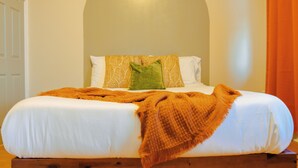 A bed with white linens, a green pillow, and an orange throw blanket. - Charming 1Br With French Door Home Theater Screen & Rain Shower (Philadelphia)