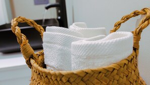 A woven basket with handles containing white towels. - Charming 1Br With French Door Home Theater Screen & Rain Shower (Philadelphia)